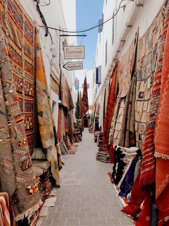 A vibrant alleyway lined with colorful carpets hanging for sale, bathed in natural light.